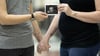 Torsos of lesbian couple with baby bump holding hands and sonogram
